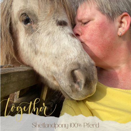 Frau küsst ein Shetlandpony, beide wirken freundlich und verbunden.